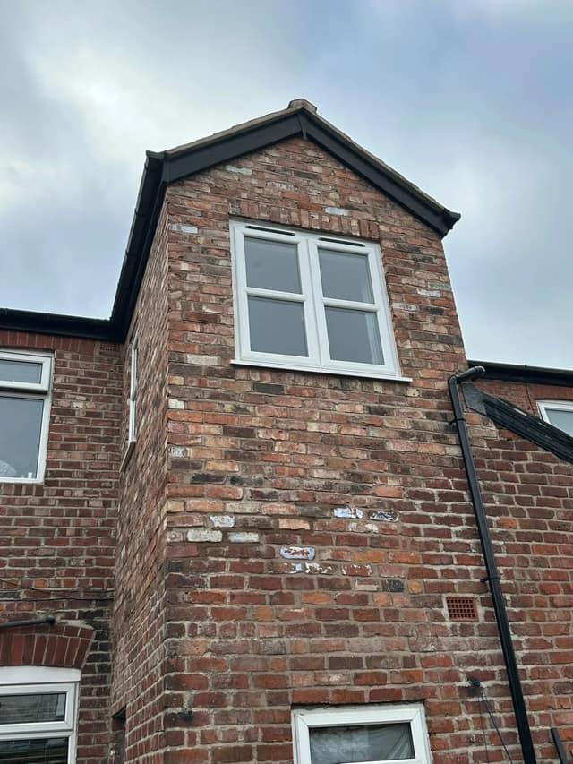 Two-storey rear projection in reclaimed-style brick with a new white uPVC window, tied into the original house