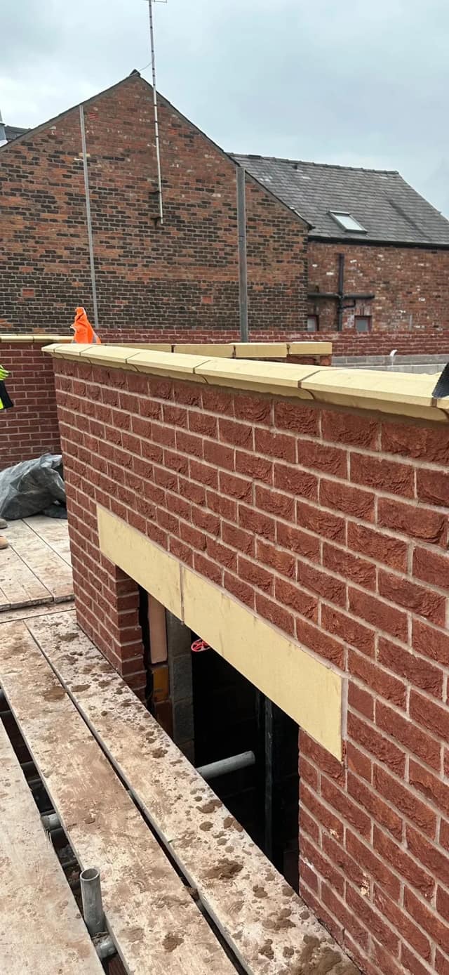 New red-brick outbuilding under construction, with the door opening formed and the lintel bedded in