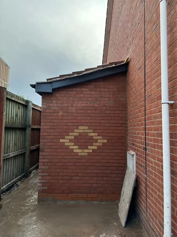 New extension brickwork with a decorative diamond feature panel, built against the existing house
