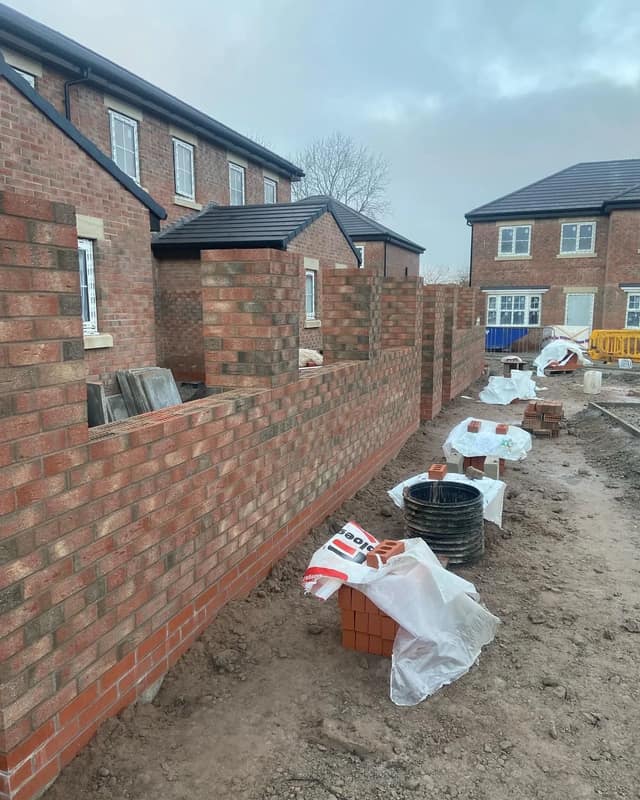 Long boundary wall in tumbled facing brick going up between plots on a new development