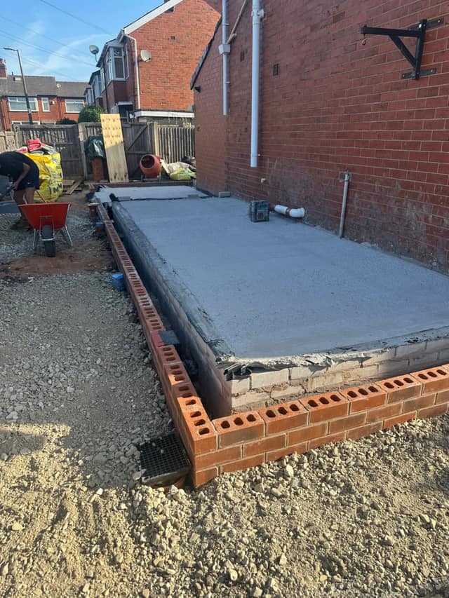 Concrete slab and footings for a rear extension, with the first courses of facing brickwork laid